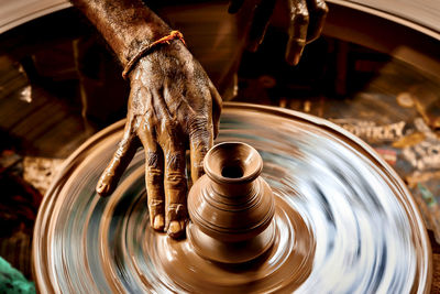 A slow shutter shot of a potter hand making a pot from a pottery wheel at hubli, karnataka, india.