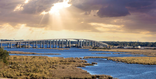 Bridge over river against sky during sunset