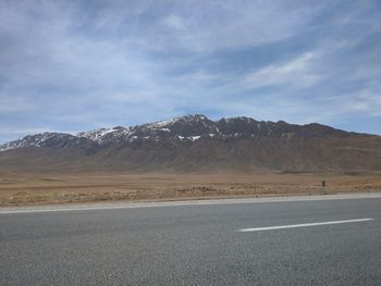 Road by mountains against sky