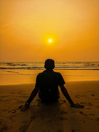 Rear view of silhouette man on beach during sunset