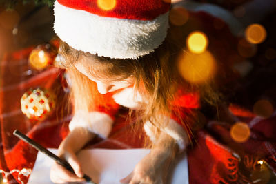 Cute girl writing on paper during christmas