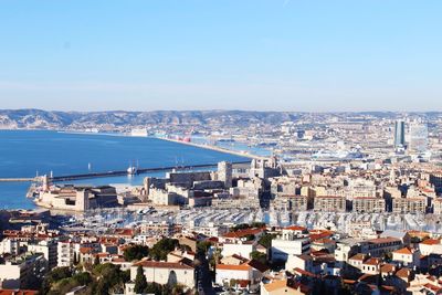 High angle view of city by sea against sky