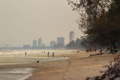 People on beach against buildings in city