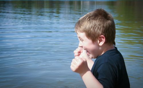 Side view of cheerful boy standing in lake