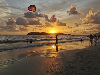 People on beach against sky during sunset