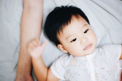 Portrait of cute baby lying on bed at home