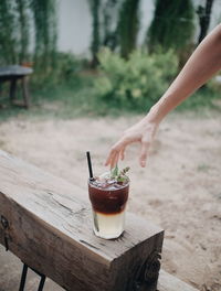 Cropped hand of woman reaching towards drink on table