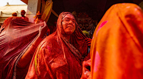 Low angle view of woman wearing sari with powder paint standing outdoors