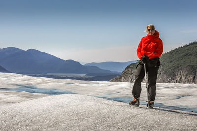 Full length of senior woman standing on snowy mountain against sky