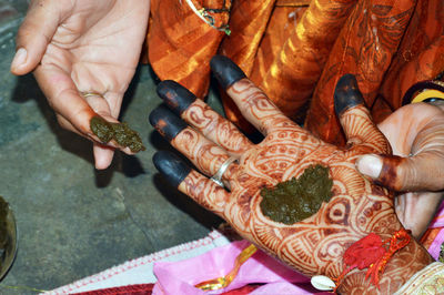 Woman put henna on groom hand to prepare indian wedding tradition called hast milap.