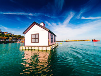 House by sea against blue sky