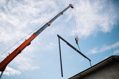 Low angle view of crane at construction site against sky