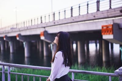 Side view of woman standing by railing
