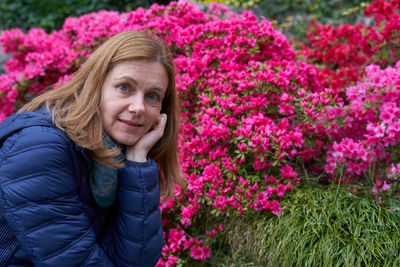 Portrait of smiling young woman standing by flowering plants