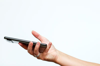 Cropped hand of person using mobile phone against white background
