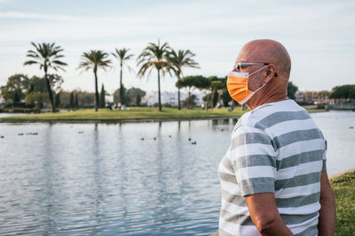 Man standing on palm tree by lake against sky