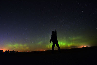 Silhouette man standing on field against sky at night