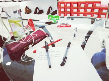 High angle view of pens and paper on glass table in shoe shop