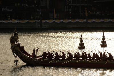 People on boat in river against built structures