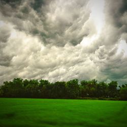 Scenic view of green landscape against cloudy sky