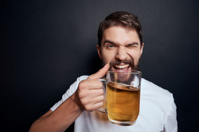 Portrait of man holding drink against black background