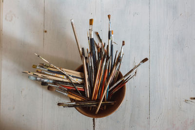 Close-up of paintbrushes in container on table against wall