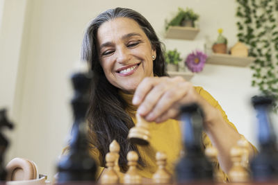 Smiling woman playing chess at home