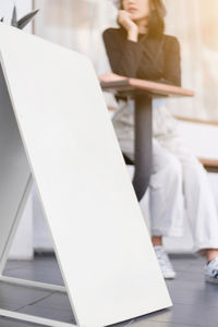 Midsection of woman using mobile phone while sitting on table