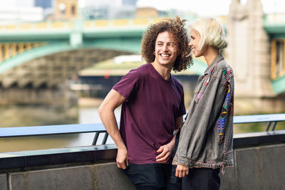 Young couple standing by railing in city