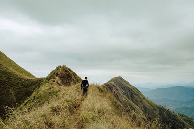 Rear view of man on mountain against sky