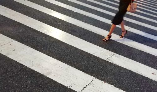 Low section of woman walking on zebra crossing