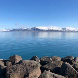 Scenic view of sea and rocks against blue sky