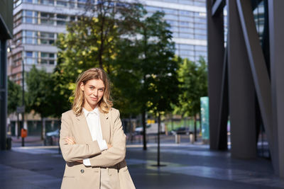 Portrait of young woman standing in city