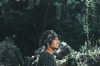 Side view of man wearing bucket hat against trees