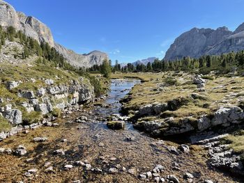 Scenic view of stream amidst rocks against sky