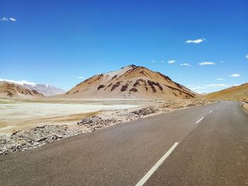 Empty road in desert against sky