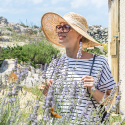 Midsection of woman wearing hat while standing by flower plants