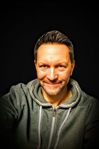 Portrait of smiling man against black background