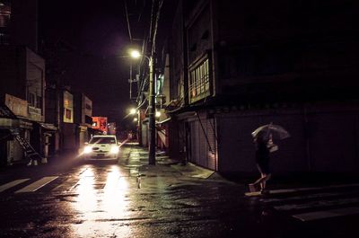 Man walking on wet illuminated city at night