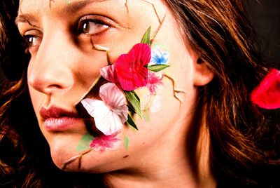 Digital composite image of flowers on woman face against black background