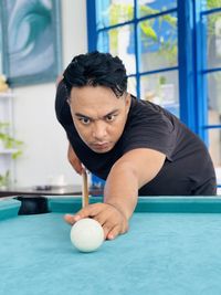 Portrait of young man with ball on table