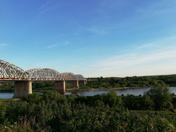 Arch bridge over river against blue sky