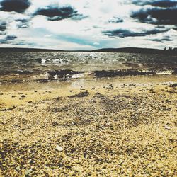 Scenic view of beach against cloudy sky