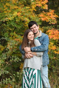 Happy young couple standing against plants