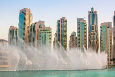 Panoramic shot of city by sea against clear sky