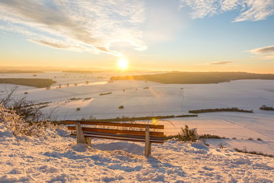 Scenic view of snow covered field against sky during sunset