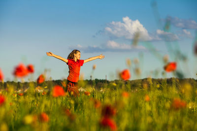 Full length of woman with arms raised on field against sky