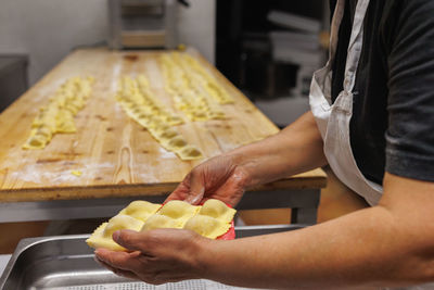 Preparing italian stuffed tortelli on a long wooden table.