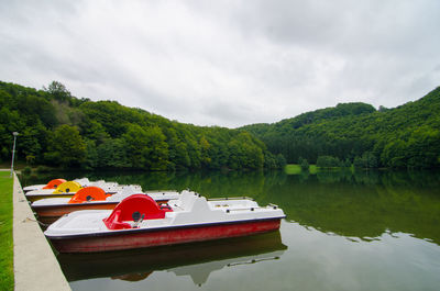 Boat moored on lake against sky