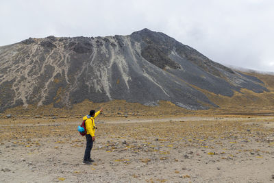 Rear view of man walking on mountain against sky